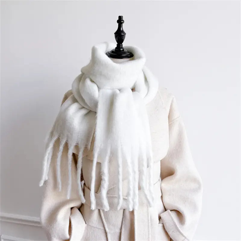 Ein flauschiger weißer Schal mit Cashmere-ähnlichem Gefühl für den Winter mit weichen, gefransten Enden, drapiert um eine Schaufensterpuppe