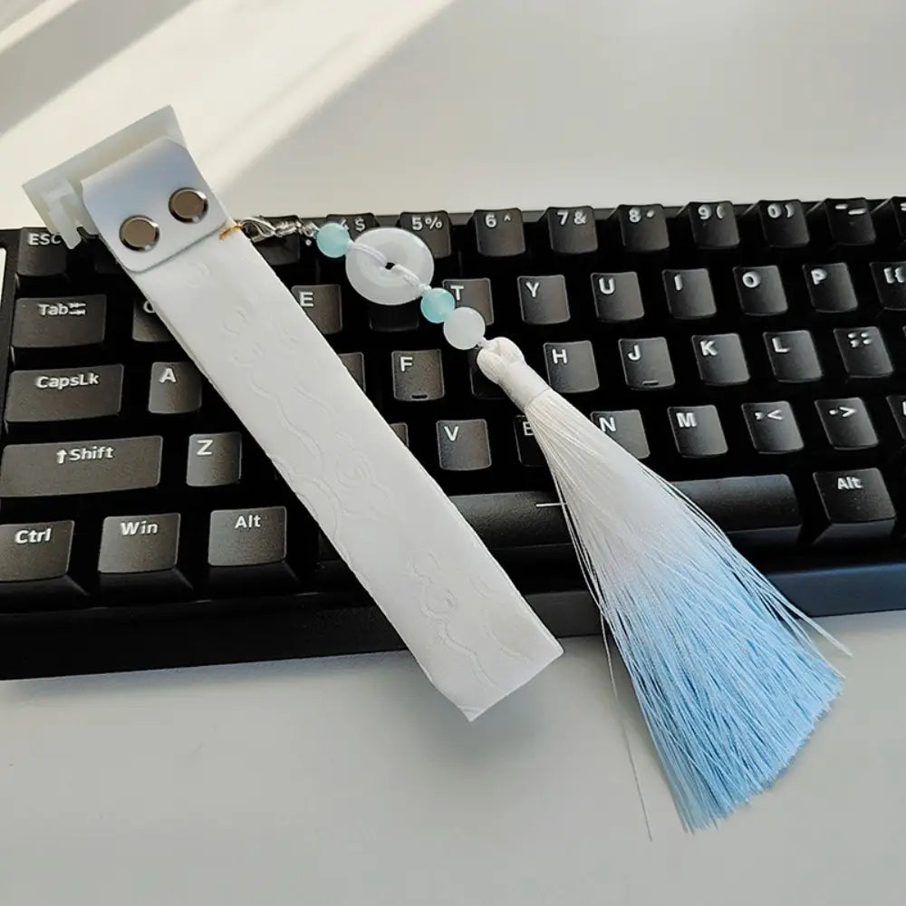 Marque-page en tissu blanc avec pompon bleu clair et perles de type jade, conçu comme une sangle personnalisée pour le modèle Ribbon Dragon du clavier Wooting.