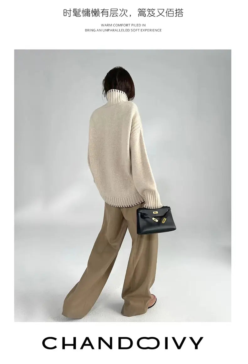 Black structured handbag with gold-tone hardware and minimalist design paired with pure wool turtleneck sweater for women.