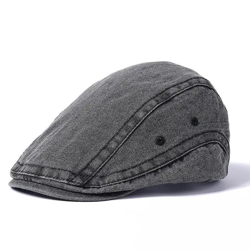 Eine dunkelgraue Denim-Flachmütze mit sichtbaren Nähten und schwarzen Knopfdetails aus der Kollektion der verstellbaren Vintage-Béret-Mützen aus Denim-Flachmütze.