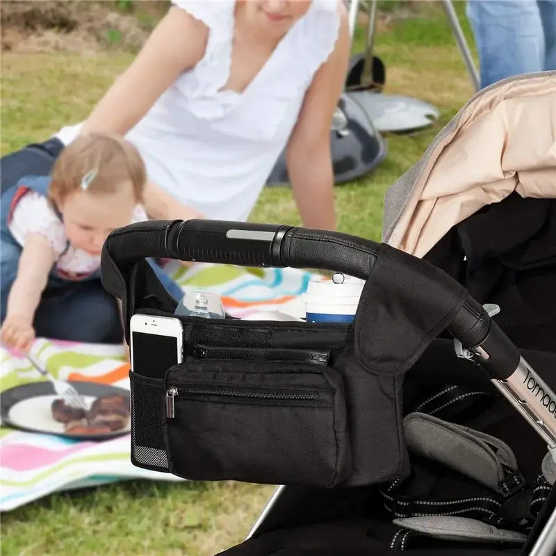 schwarze Babywagen-Organizer-Tasche, hohe Kapazität, mit mehreren Reißverschlussfächern und einer Mesh-Tasche, ausgelegt zur sicheren Befestigung am Lenker.