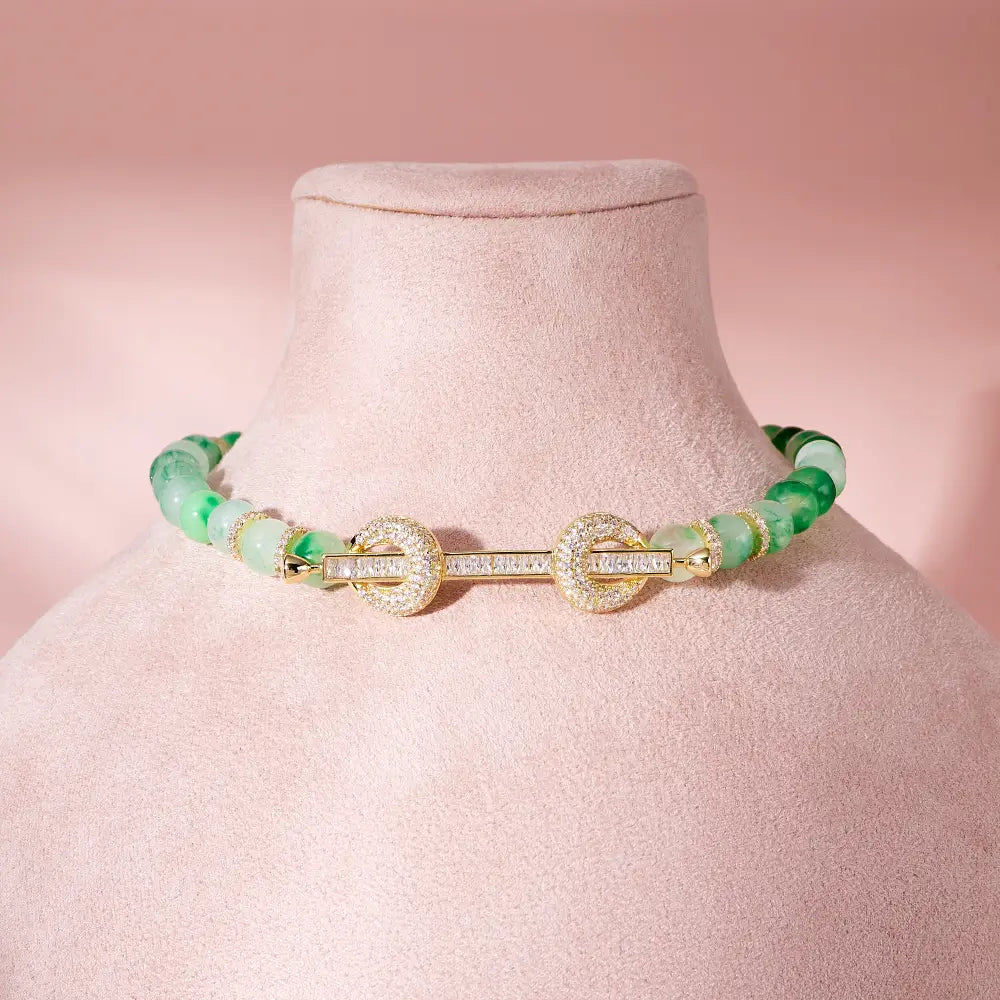 Elegante collar tipo choker de jade y dorado con cuentas, con un broche central engastado con diamantes y acentos de circonita cúbica.