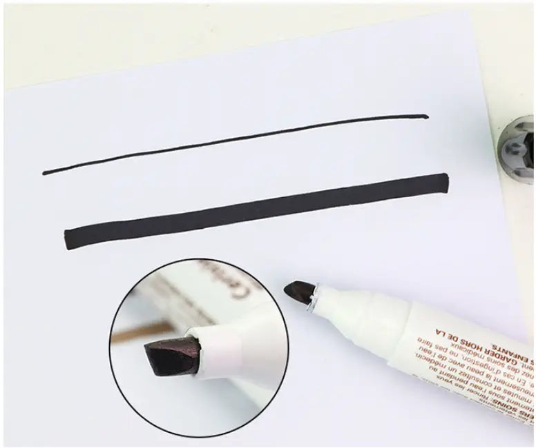 Weißer Möbelreparierstift mit schwarzer Meißel-förmiger Tintenmine, dargestellt beim Zeichnen von zwei parallelen Linien auf Papier zur Reparatur von Holzkratzern
