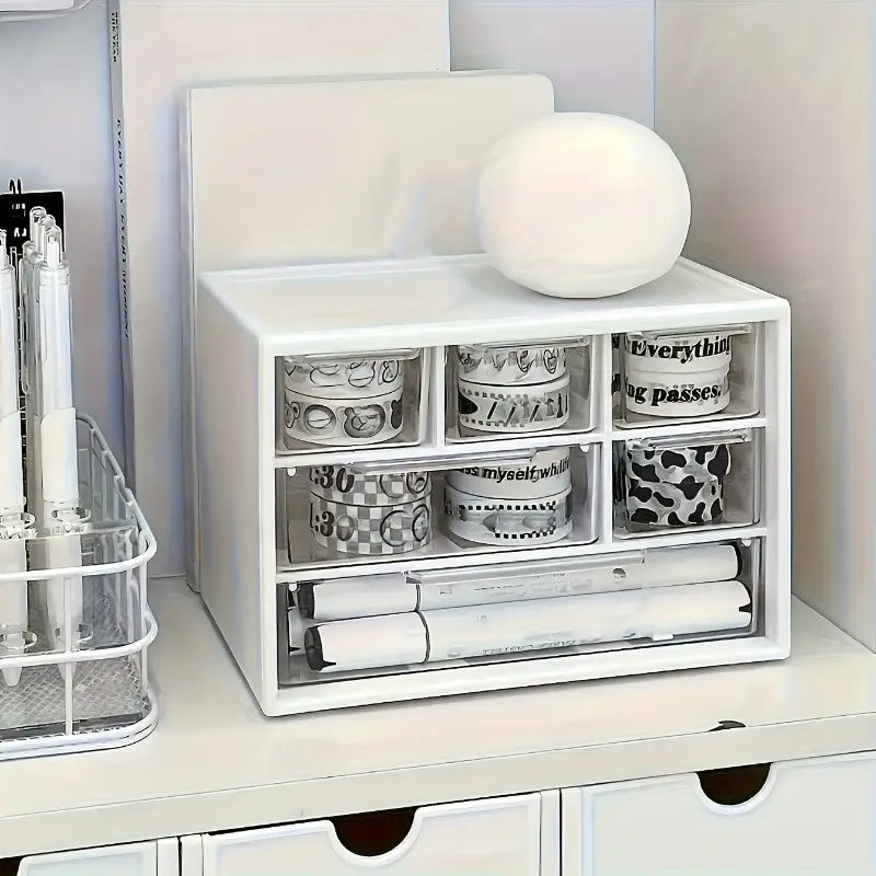 Organisateur de bureau en plastique blanc avec tiroirs transparents, comprenant plusieurs compartiments pour ranger des rouleaux de ruban washi et des marqueurs.
