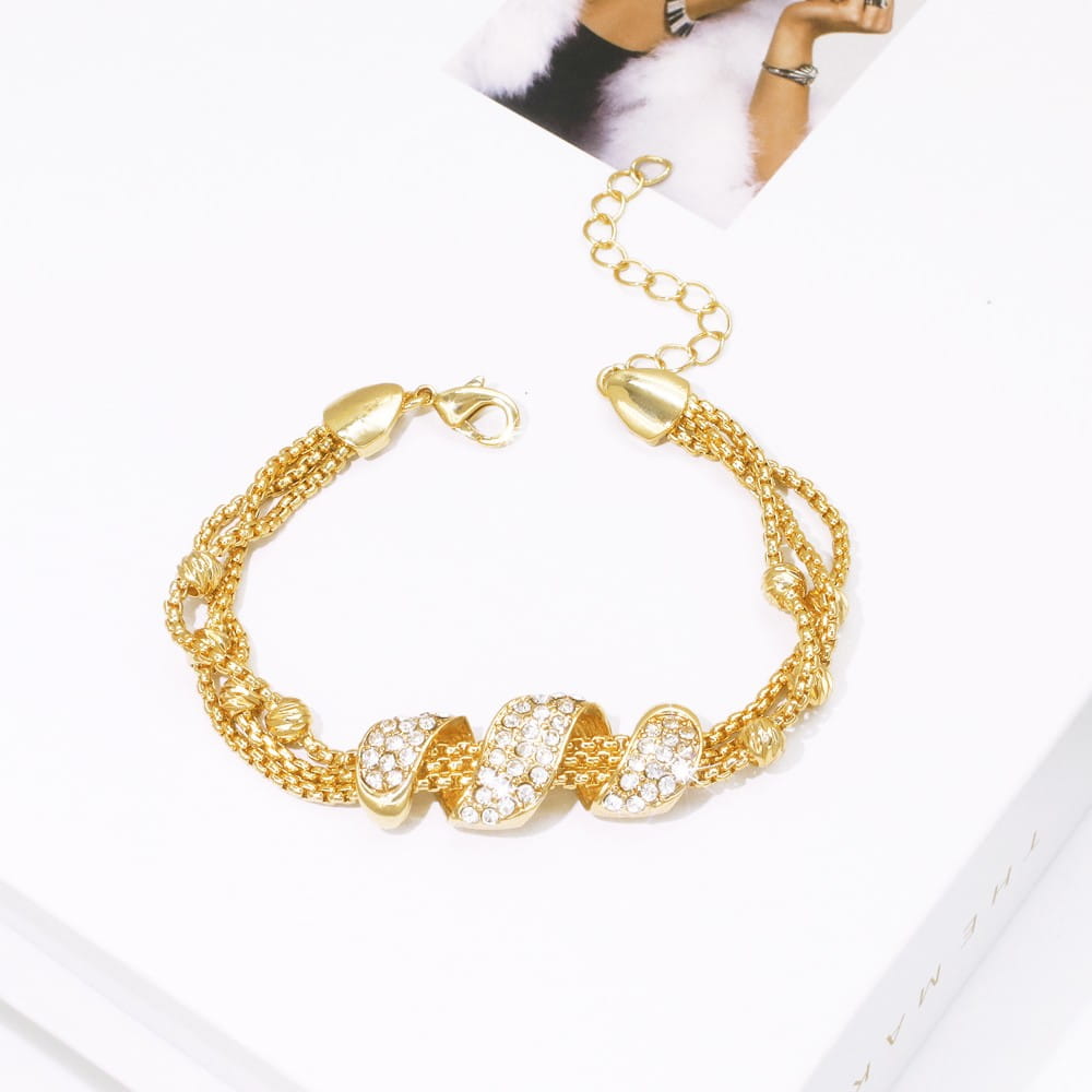 Goldtöniges Armband aus dem Goldquasten-Schmuckset für Damen mit mehrreihigem Design, verdrehten, kristallbesetzten zentralen Elementen und strukturierten Kettengliedern.