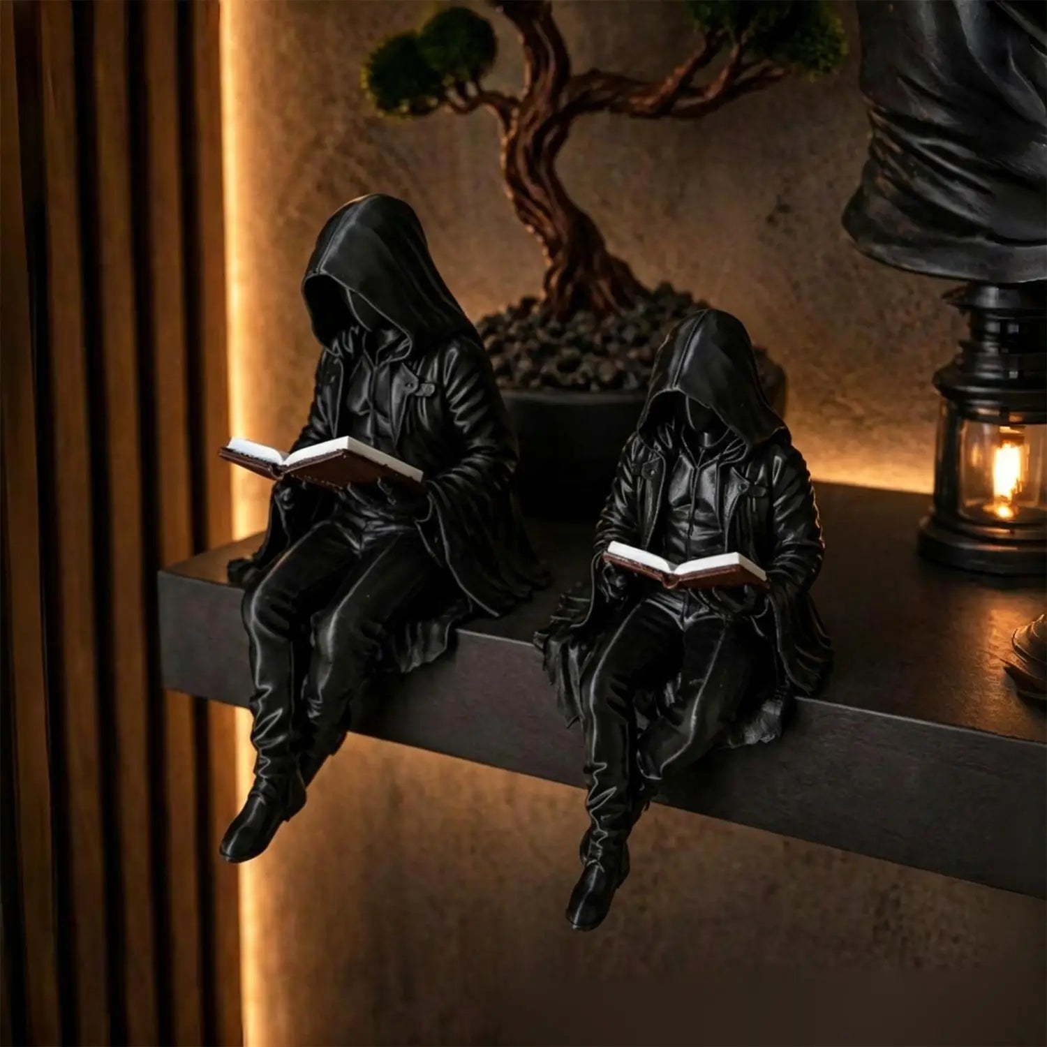 zwei schwarze, glänzende, kapuzengetragene Gothic-Leserfiguren, die jeweils auf einem Regal sitzen und jeweils ein offenes Buch halten, Gothic-Leserfigur, unheimliche Bücherregal-Statue