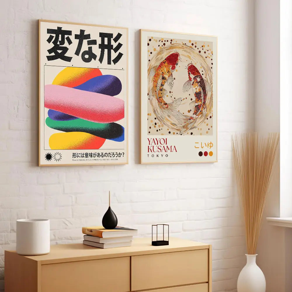 Dos pósteres artísticos enmarcados cuelgan en una pared de ladrillo blanco y presentan caracteres japoneses negros en negrita, con bandas de color abstractas y vibrantes, junto con una impresión en lienzo de un pez koi japonés con detalles de koi en círculos concéntricos sobre un fondo color marfil.
