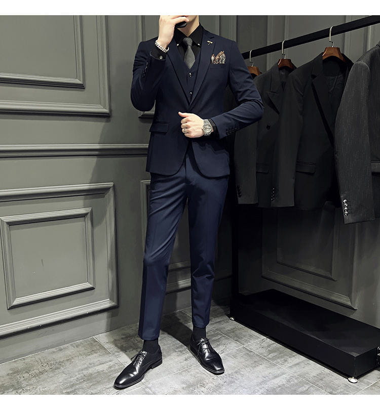 Ensemble de costume trois pièces slim fit pour homme bleu marine, avec texture discrète et pochette de costume assortie, comprenant 9 pantalons courts à la cheville et un type de fermeture par boutons.