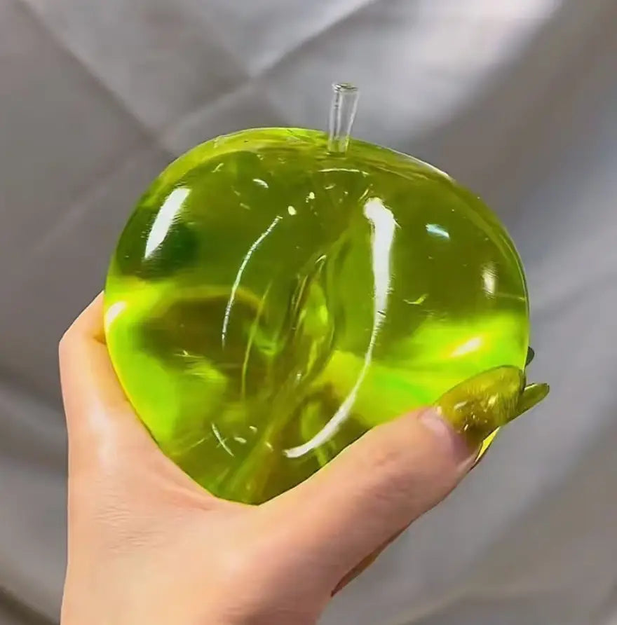 une balle anti-stress souple verte en forme de pomme vert citron translucide, avec une tige transparente, vue de face