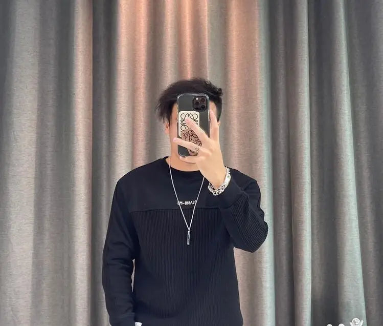 Pull-over en maille côtelée noire avec un empiècement texturé contrastant sur la poitrine, manches complètes, conçu comme un pull-over en maille à empiècement contrastant pour homme.