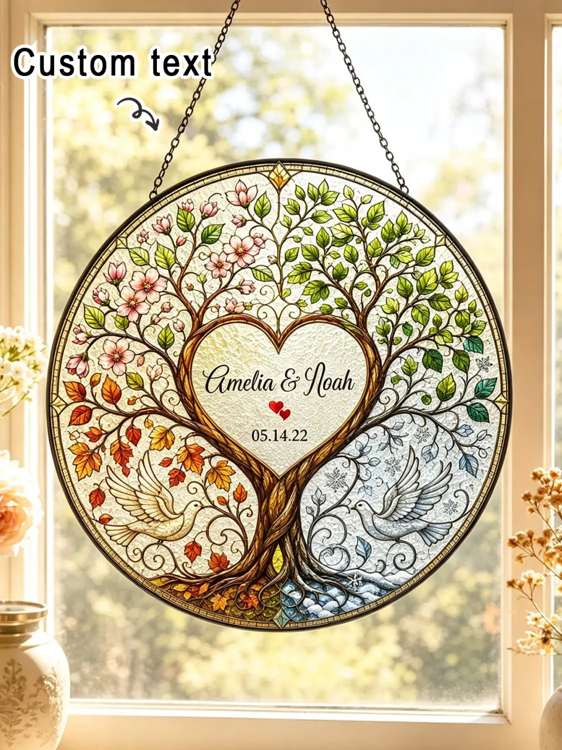 Decoración colgante de ventana circular de vitrales que presenta un árbol de la vida con cuatro estaciones en verdes vivos, rosas, naranjas y azules, y un centro en forma de corazón inscrito con nombres y fecha, personalizado como regalo de boda.