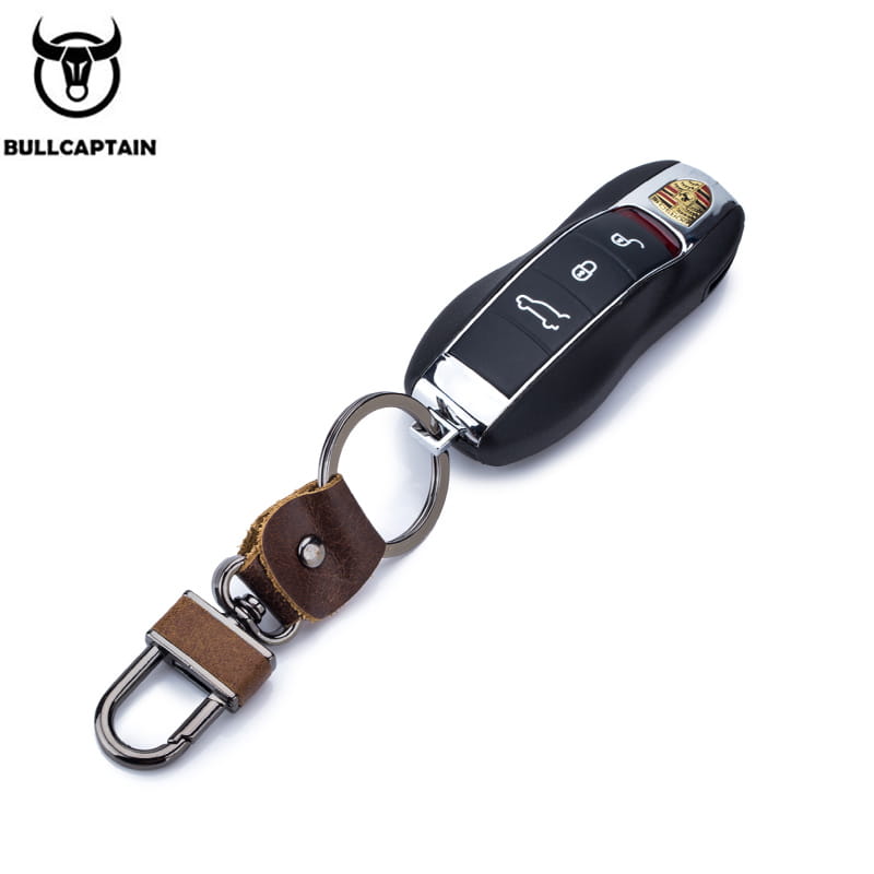 Black leather car key chain brown bullcaptain keychain with silver-toned metal ring and carabiner featuring attached Porsche remote fob.