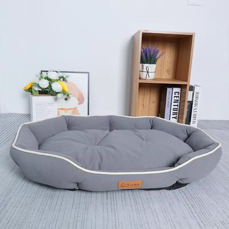 Large pink plush sofa sleeping bed for dogs in gray with white piping and a small orange brand tag.