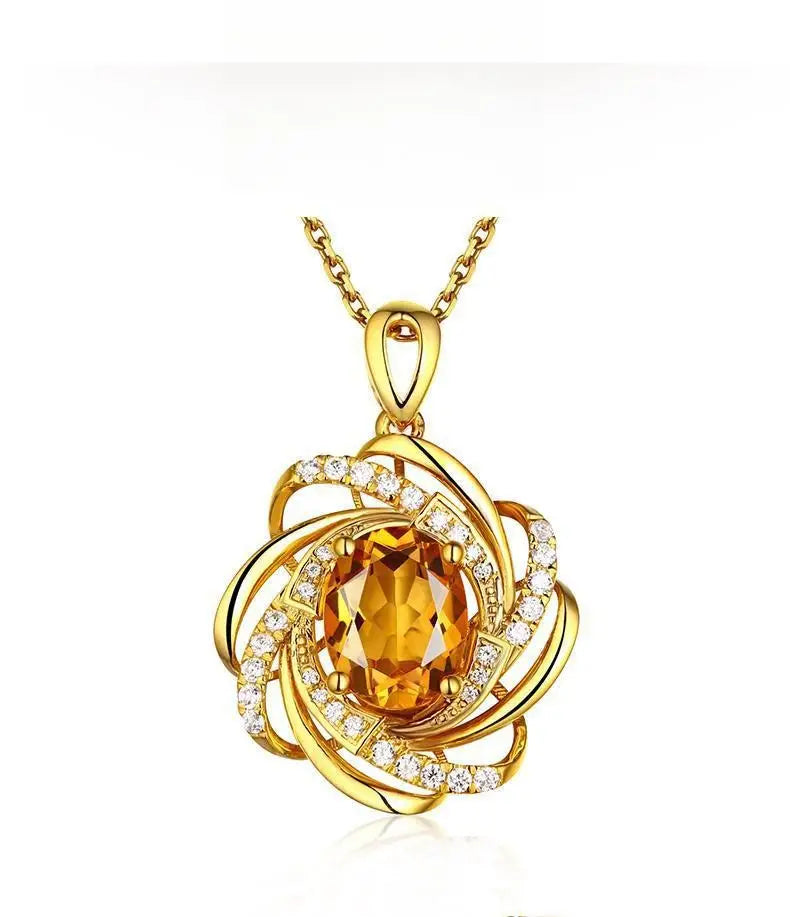 Collier pendentif moulin à vent en citrine doré comportant une pierre ovale centrale en citrine entourée de bandes dorées tourbillonnantes et de petits diamants, suspendue à une chaîne dorée assortie.