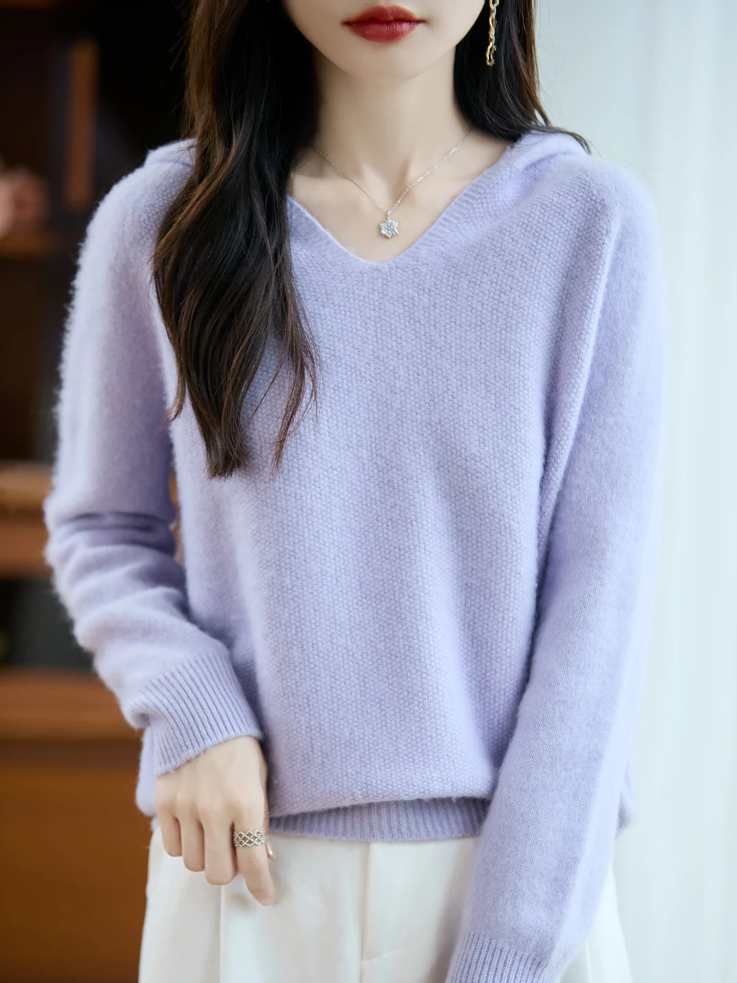 A soft lavender-colored pure wool hooded pullover sweater featuring a cozy knit texture and ribbed cuffs with long sleeves and a v-neck.