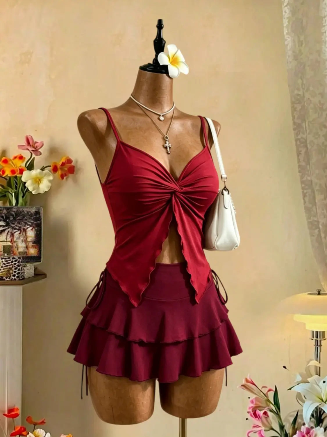 Ein kräftig rotes Y2K-Zweiteiler-Outfit mit hoher Taille und Bindeband, bestehend aus einem gerafften Tanktop mit vorderem Knoten und passenden mehrlagigen Shorts, an einer Schaufensterpuppe präsentiert.