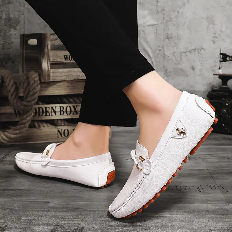 Les chaussures à enfiler habillées en cuir se portent sans effort avec des chaussures décontractées en cuir blanc, avec un emblème équestre ton or et des semelles en caoutchouc orange.
