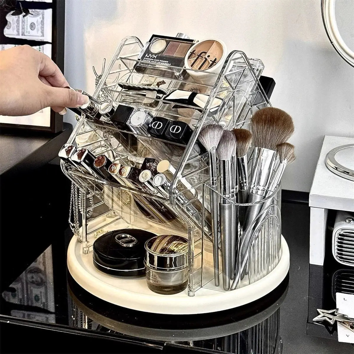 Organisateur de maquillage en acrylique transparent rotatif, doté de plusieurs compartiments, d’une base rotative et de supports pour pinceaux à finition ton argent.