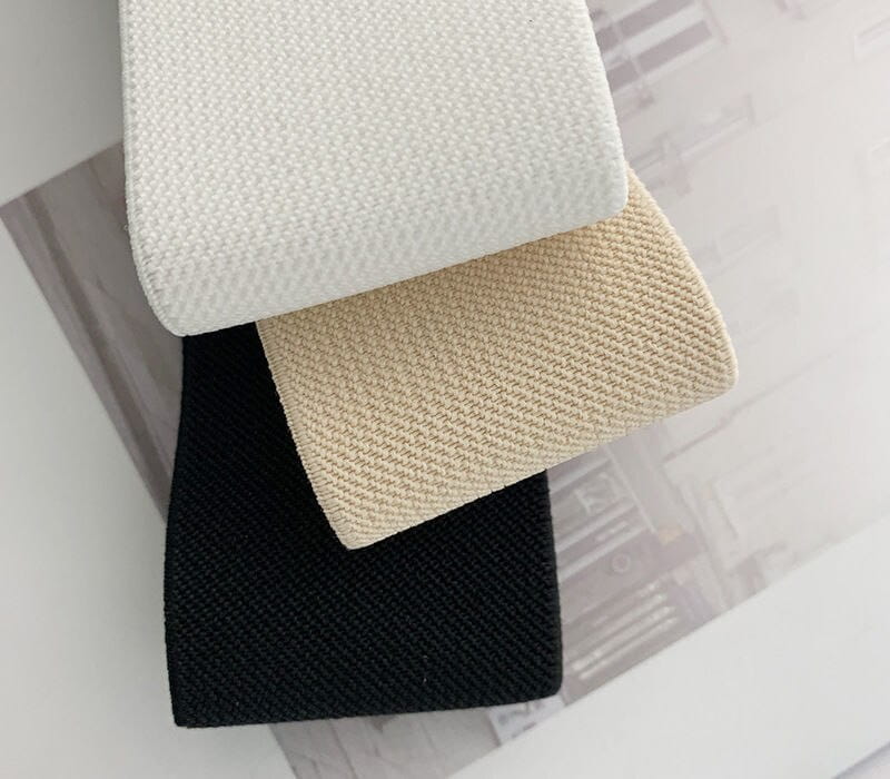 Drei rechteckige, gewebte Stoffmuster in Weiß-Beige und Schwarz für einen Damen-Elastikgürtel mit runder Schnalle für den Taillenbund bei Modekleidern.
