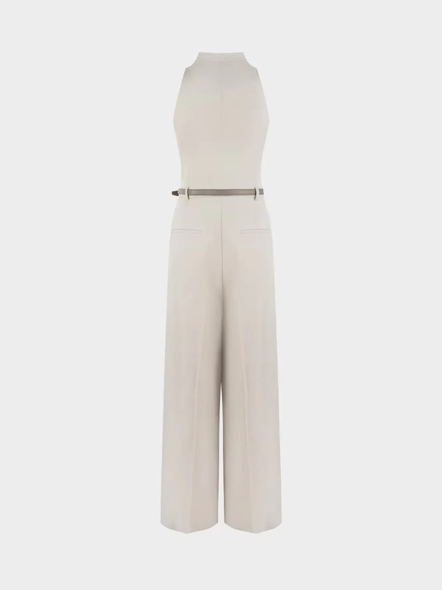 Une combinaison beige à col halter et jambes larges de couleur crème, présentant un design sans manches, un pantalon à jambes larges et une ceinture métallique fine.