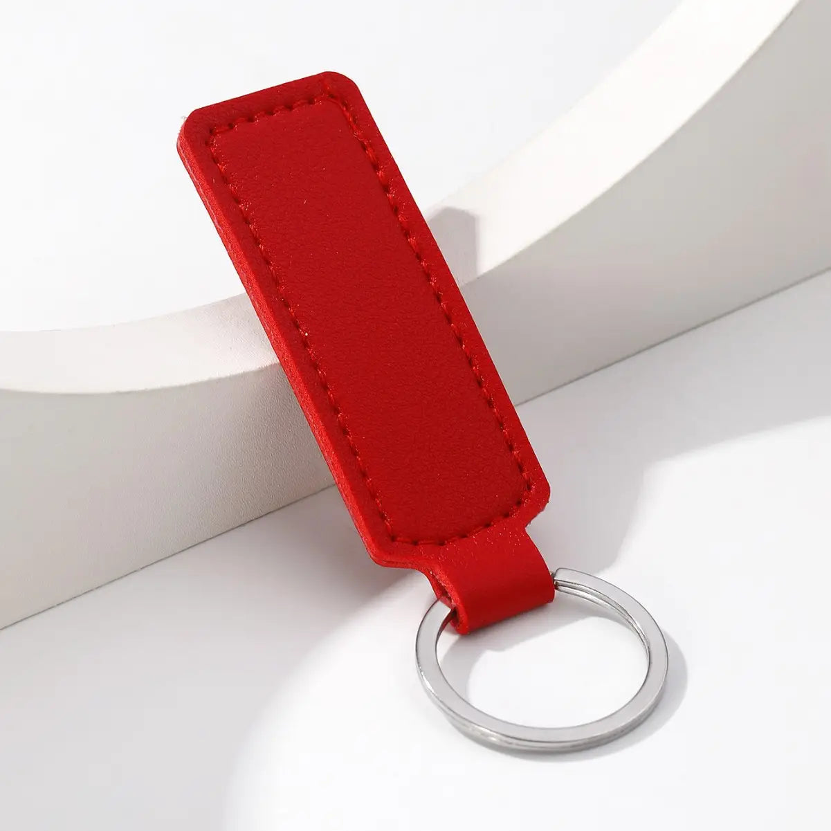 Red rectangular leather minimalist strip key ring with a silver metal ring for car keys.
