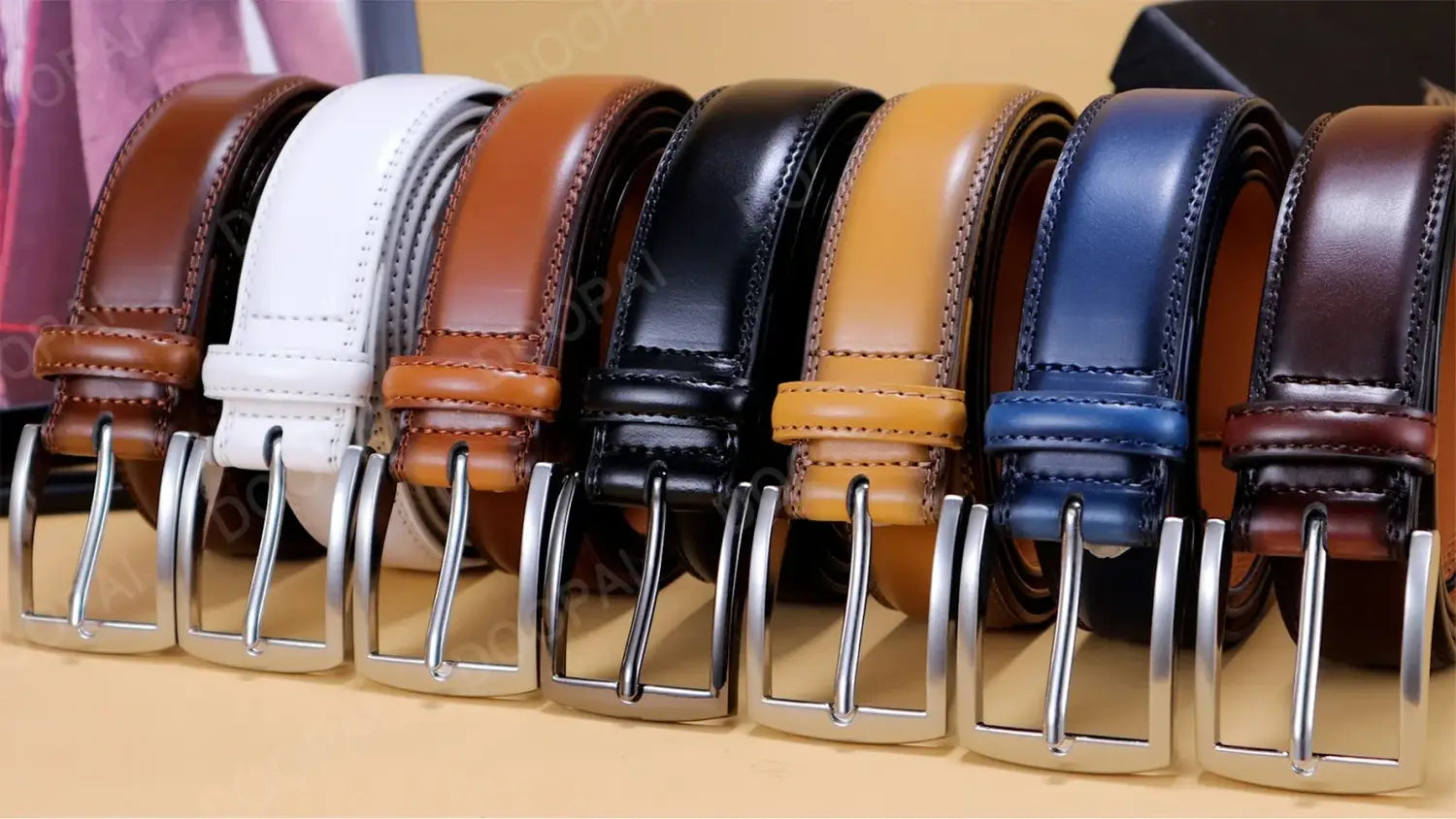 Collection de six ceintures à cliquet en cuir pour homme avec des boucles en métal à l’aspect argenté automatique, dans les couleurs brun, blanc, noir, beige, bleu et bordeaux foncé.