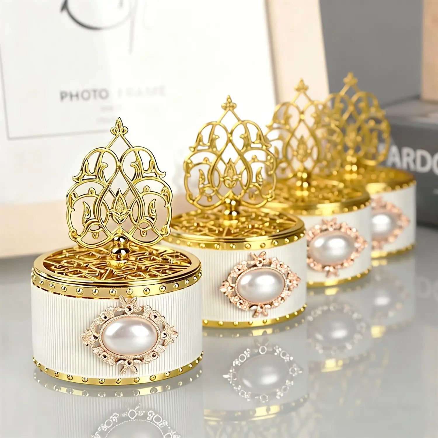 Coffret à musique blanc et or élégant, orné et détaillé, avec un dessus en filigrane raffiné, des rehauts de perles et des côtés cannelés, servant de boîte à bonbons de mariage dorée décorative, contenant une perle-bonbon en guise de cadeau.