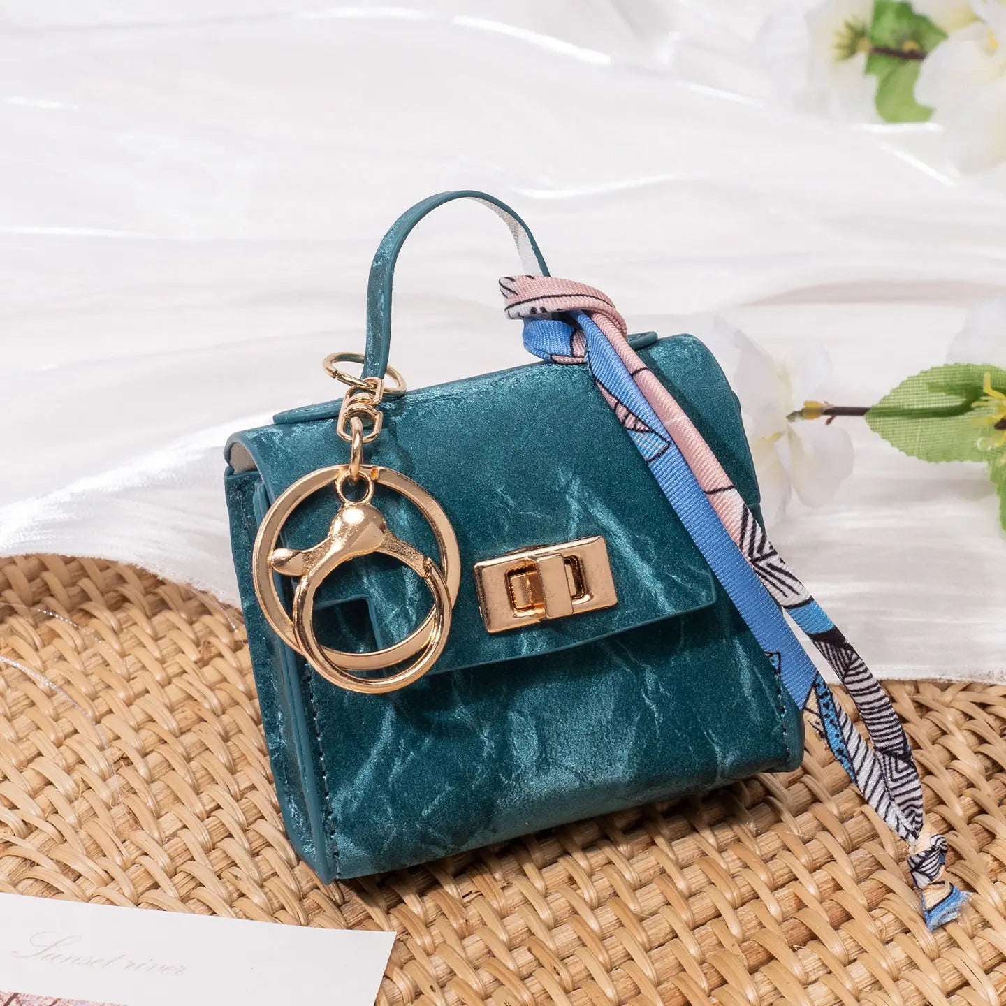 Teal velvet miniature handbag keychain with gold-tone hardware and patterned silk scarf strap.