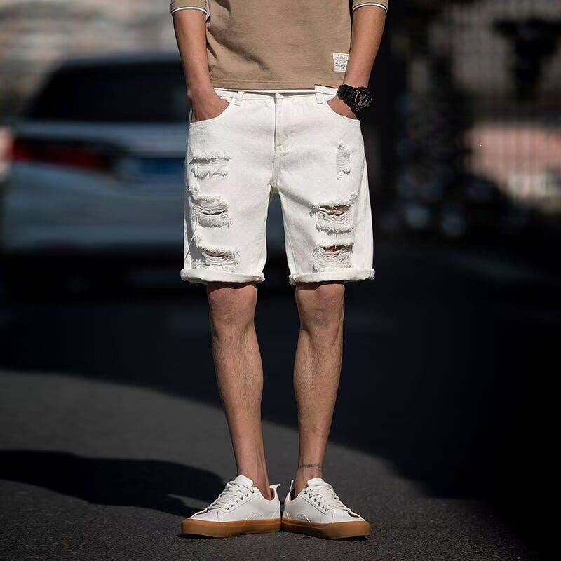 Les shorts en jean blanc déchiré présentent un denim blanc vieilli avec des revers roulés, conçus pour le streetwear.