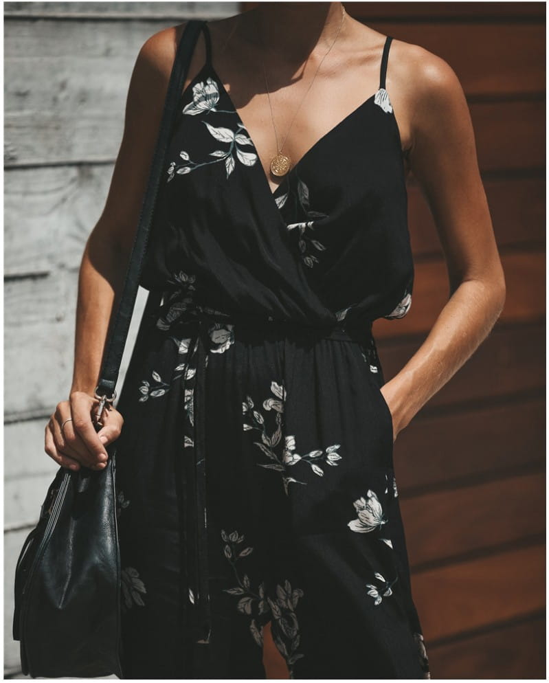Schwarzer Boho-Sommeroverall mit Blumendruck in Wickeloptik, mit schmalen Trägern und einer taillierten Form; für einen stilvollen und bequemen Look.