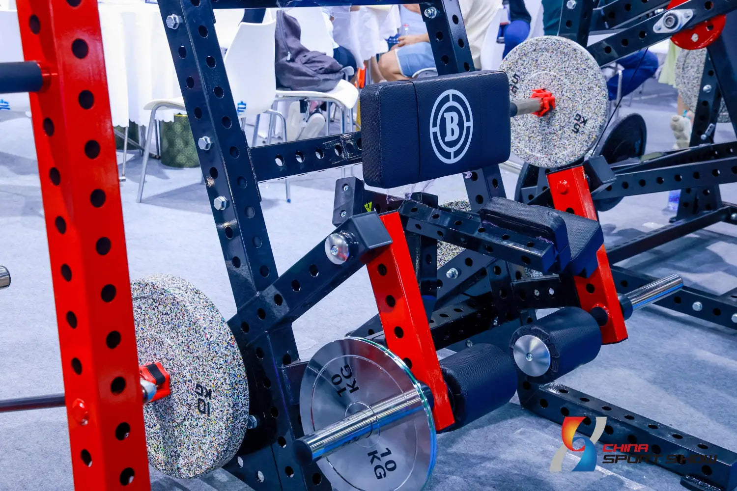 Commercial stair climber machine cardio stepmill shown from the back with a black and red adjustable squat rack featuring weight plates and a branded backrest.