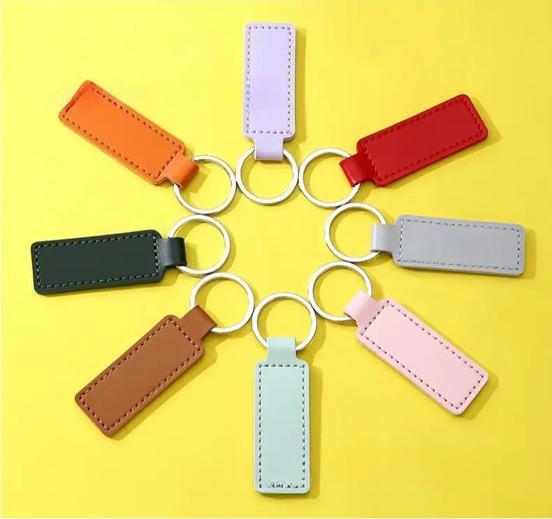 a set of eight customized leather keychains in assorted pastel and earthy tones featuring stitched edges and attached to silver-toned metal rings