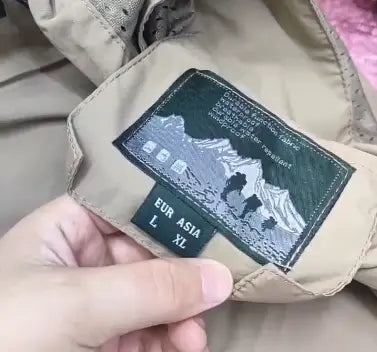 etiqueta interior de la chaqueta color beige con una escena montañosa bordada en verde oscuro e indicador de talla en chaquetas cortavientos impermeables para hombre Naturehike, modelo verde oliva