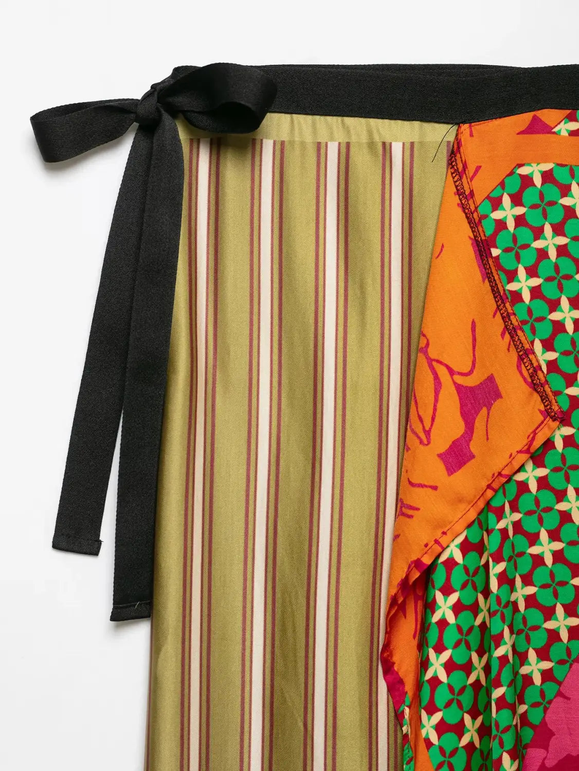 A floral print two piece midi skirt set featuring a vibrant patchwork-style skirt with vertical stripes in olive green and beige and a contrasting orange panel with geometric patterns.
