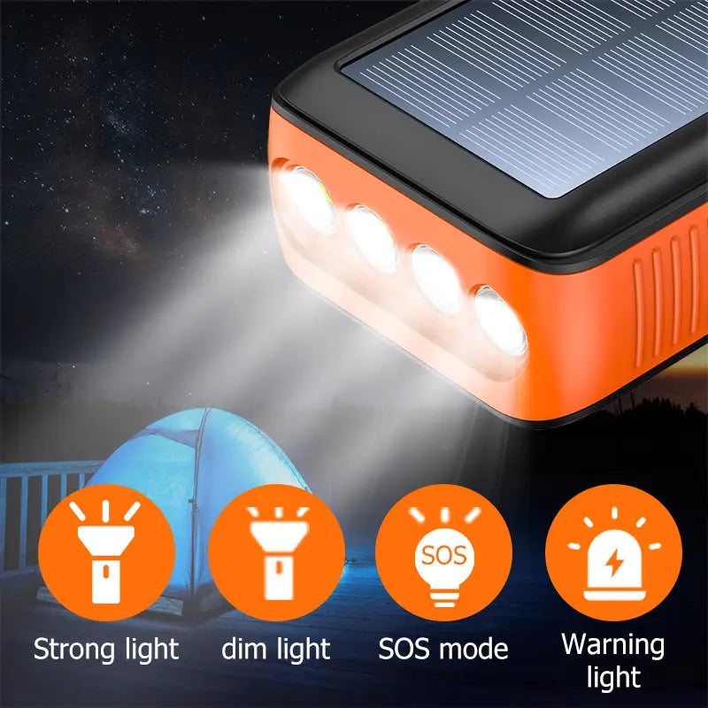 オレンジおよびブラックのソーラーパワーバンク、手回し式、防水LEDライト付き。4つの高輝度LEDを搭載し、信頼性のあるソーラー電源および緊急時の使用に適しています。