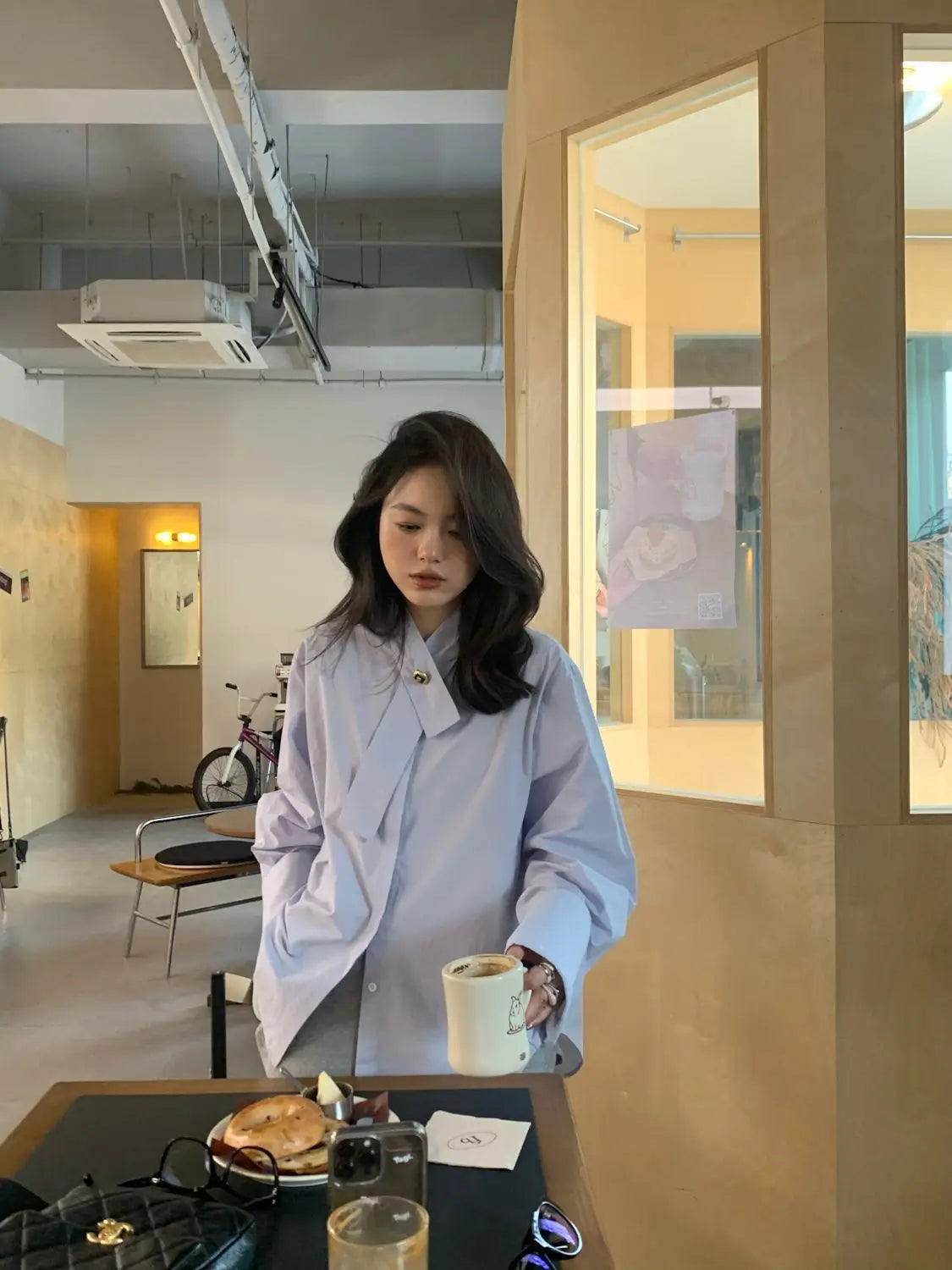 A woman wearing a light blue oversized button up shirt with a distinctive collar and cuffs.