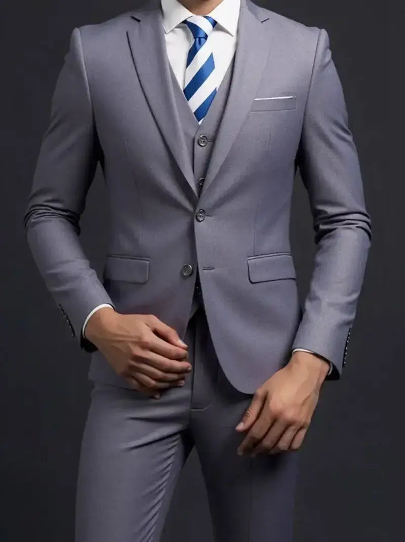 Un traje de tres piezas de hombre gris, a medida, de un solo pecho para vestir formal, que incluye un chaleco y pantalones a juego, con camisa de vestir blanca y corbata azul de rayas diagonales, enfatizando un tipo de cierre de un solo botón.