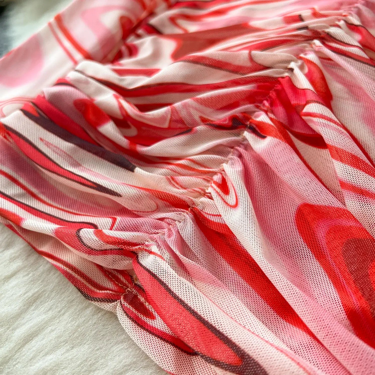 a two piece mesh skirt set with a flowing semi transparent dress featuring a vibrant red and pink abstract swirl marble print on a sheer mesh base with elastic closure type