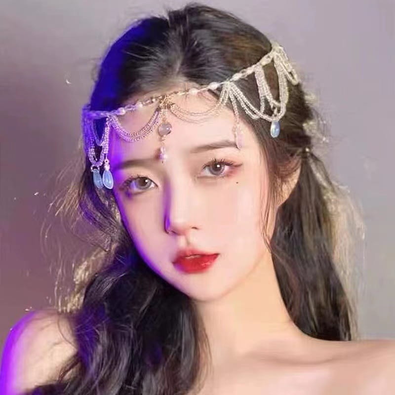 赤い宝石のゴールド前髪チェーンヘアペンダントという題名のデザインに、揺れる青い雫型ビーズと精巧なチェーンワークで飾られた、繊細なシルバートーンの前髪チェーンヘアペンダントです。