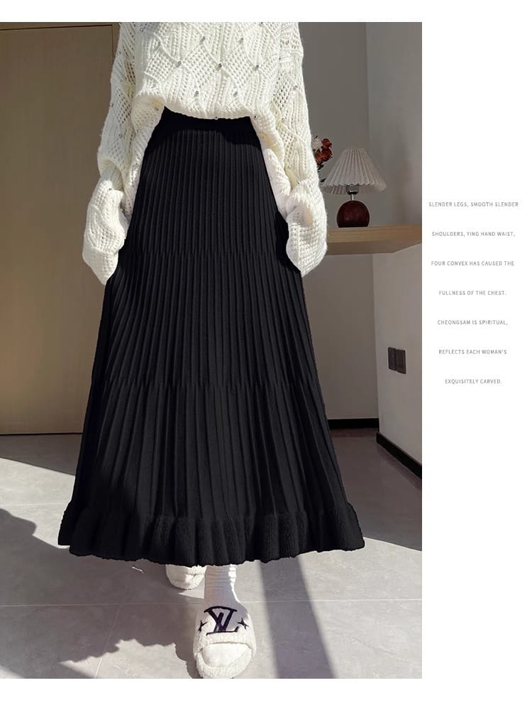 Jupe mi-longue en maille noire, à taille haute, plis, ceinture lisse et ourlet volanté dans une silhouette parapluie