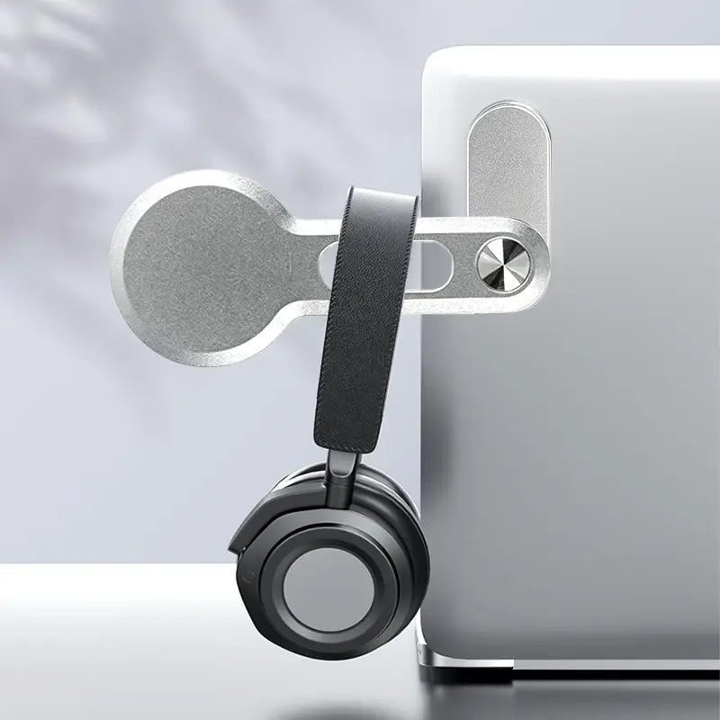 Silberner metallischer Magnet-Phonehalter mit schwarzem Lederband, das über die Kante eines Laptops auf einem Aluminium-Ständer gesichert wird