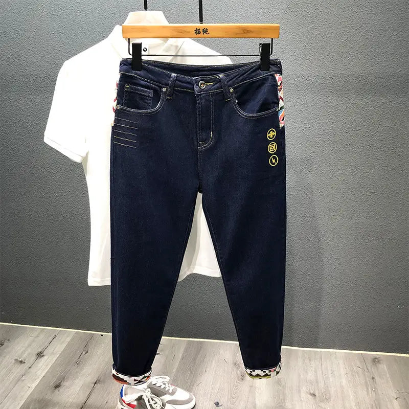 Men slim fit stretch embroidered white denim jeans in dark blue featuring circular embroidered motifs on the side and patterned cuffs.