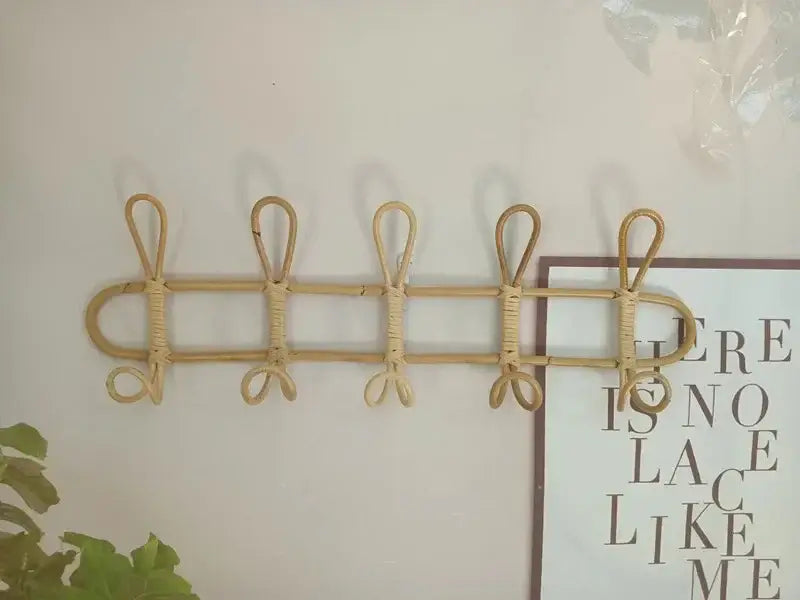 Rattan-Kinder-Wandhaken zur Aufbewahrung von Kleidung in natürlichen Farbtönen mit fünf gleichmäßig verteilten, wandmontierten Haken.