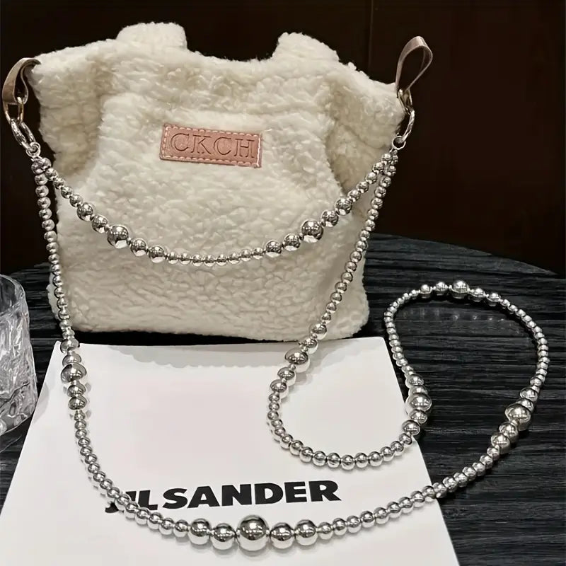 Bolso tipo bombonera de piel vuelta esponjosa color crema con correa para colgante de teléfono con cuentas plateadas y parcho de cuero marrón con el logotipo ckch.