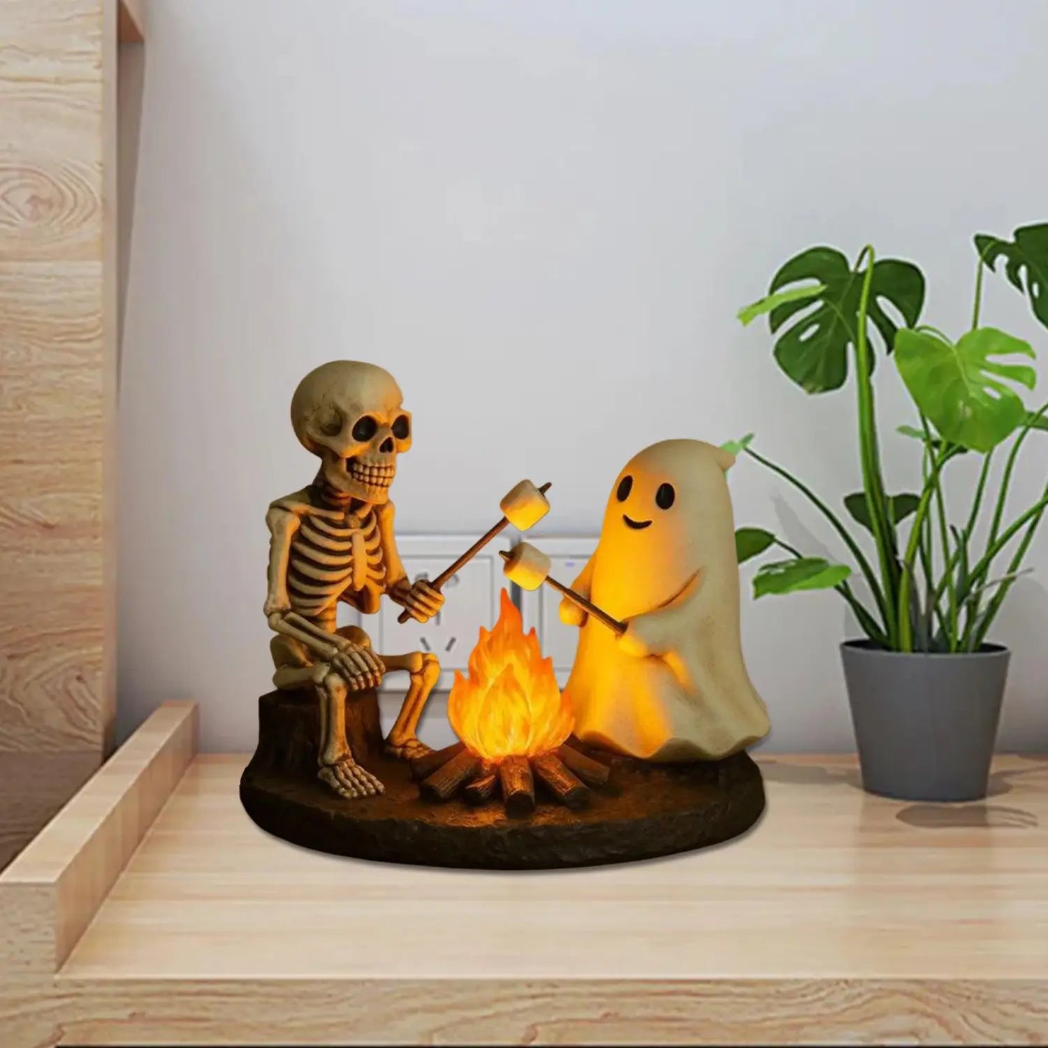 une lanterne de nuit de feu de camp fantomatique lumineuse : elle présente un fantôme squelette éclairé et une figurine de fantôme rôtissant des guimauves au-dessus d’un feu de camp, pour la décoration d’Halloween.