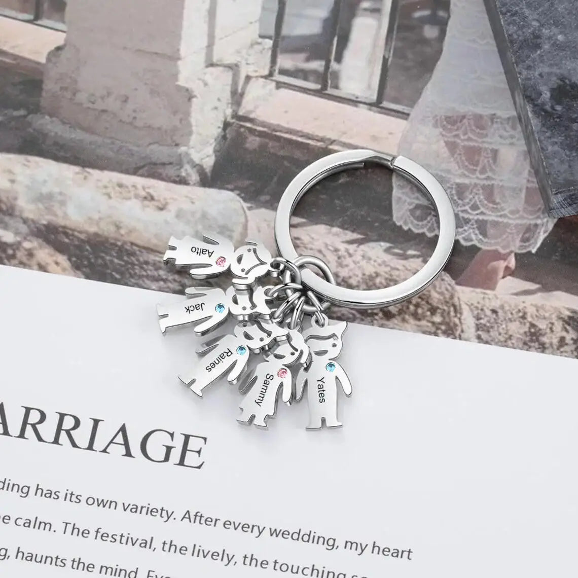 Personalized family keychain made of silver with custom engraved child figures and colorful gemstone accents.