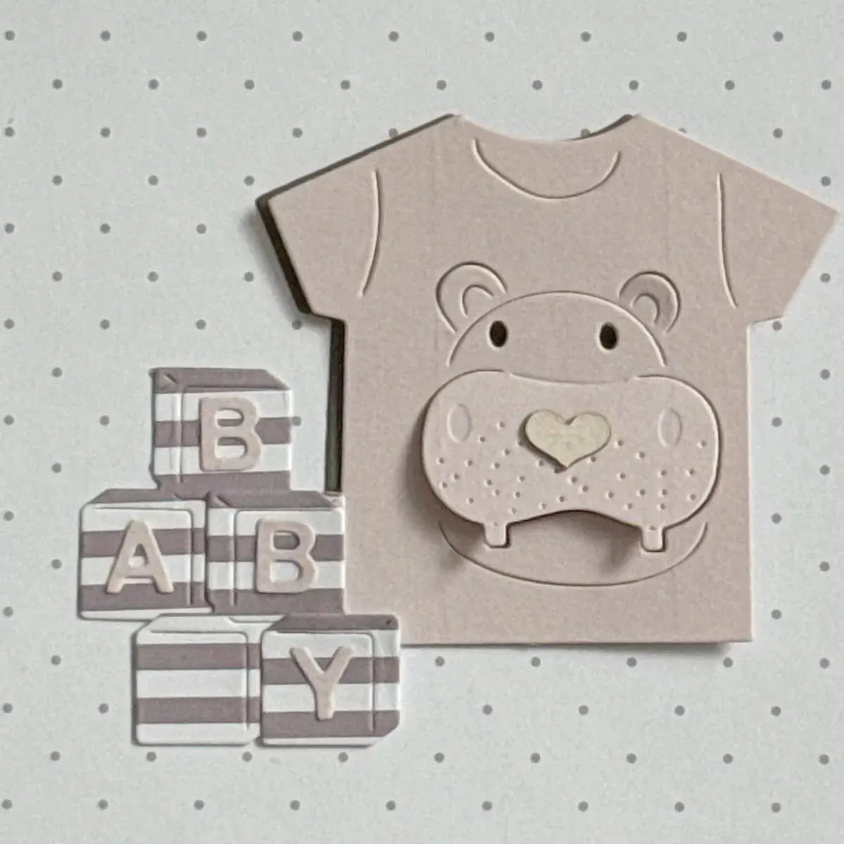 eine beigerfarbene Papierschneidvorlage für einen Babybody mit einem erhabenen Flusspferdkopf und einer herzförmigen Nase aus der Kollektion Oster-Ei-Hasen-Babyschneidvorlagen