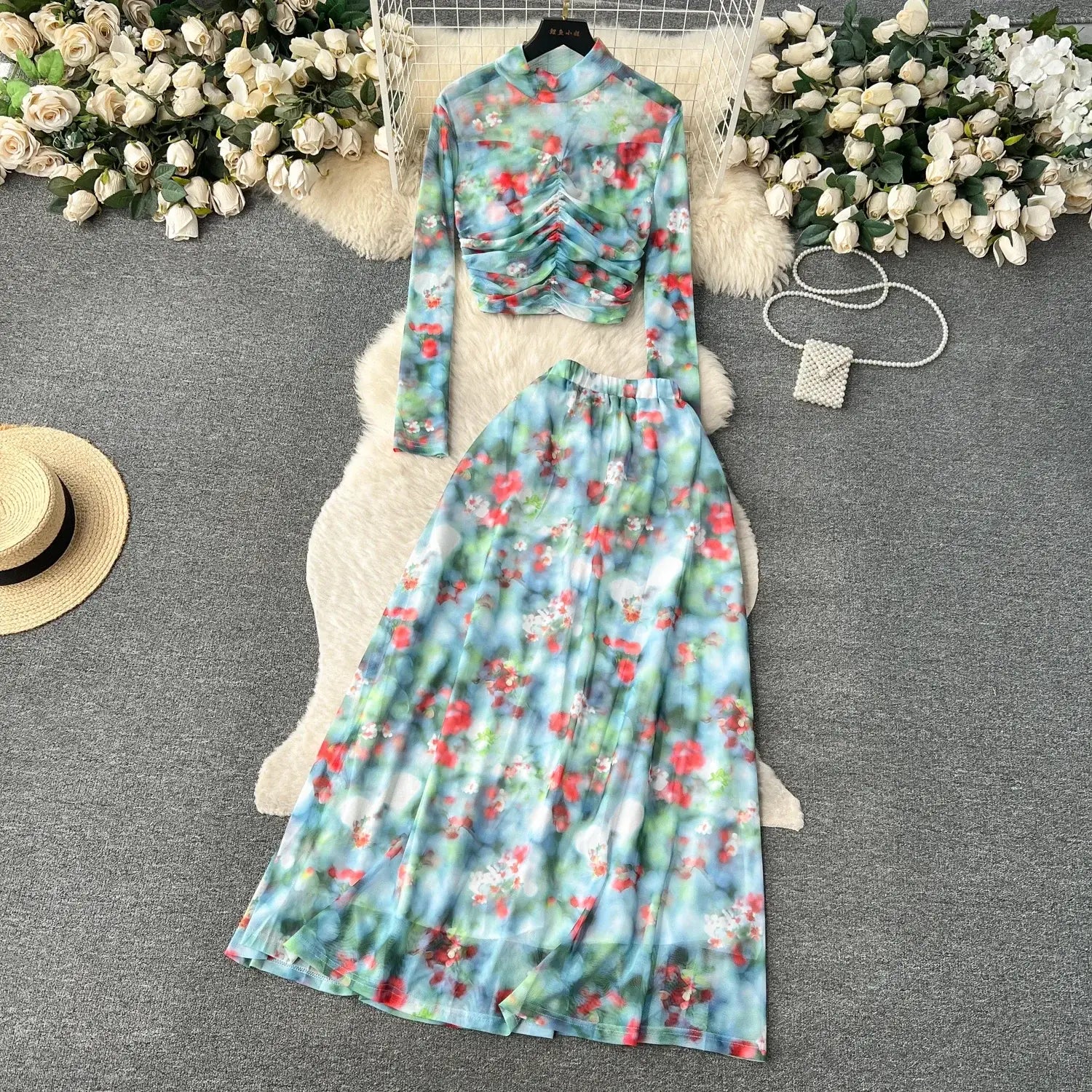 a two-piece mesh skirt set with a marble print featuring a high-neck long-sleeved ruched top and a flowing maxi skirt in pastel blue, green, and red tones with elastic closure type
