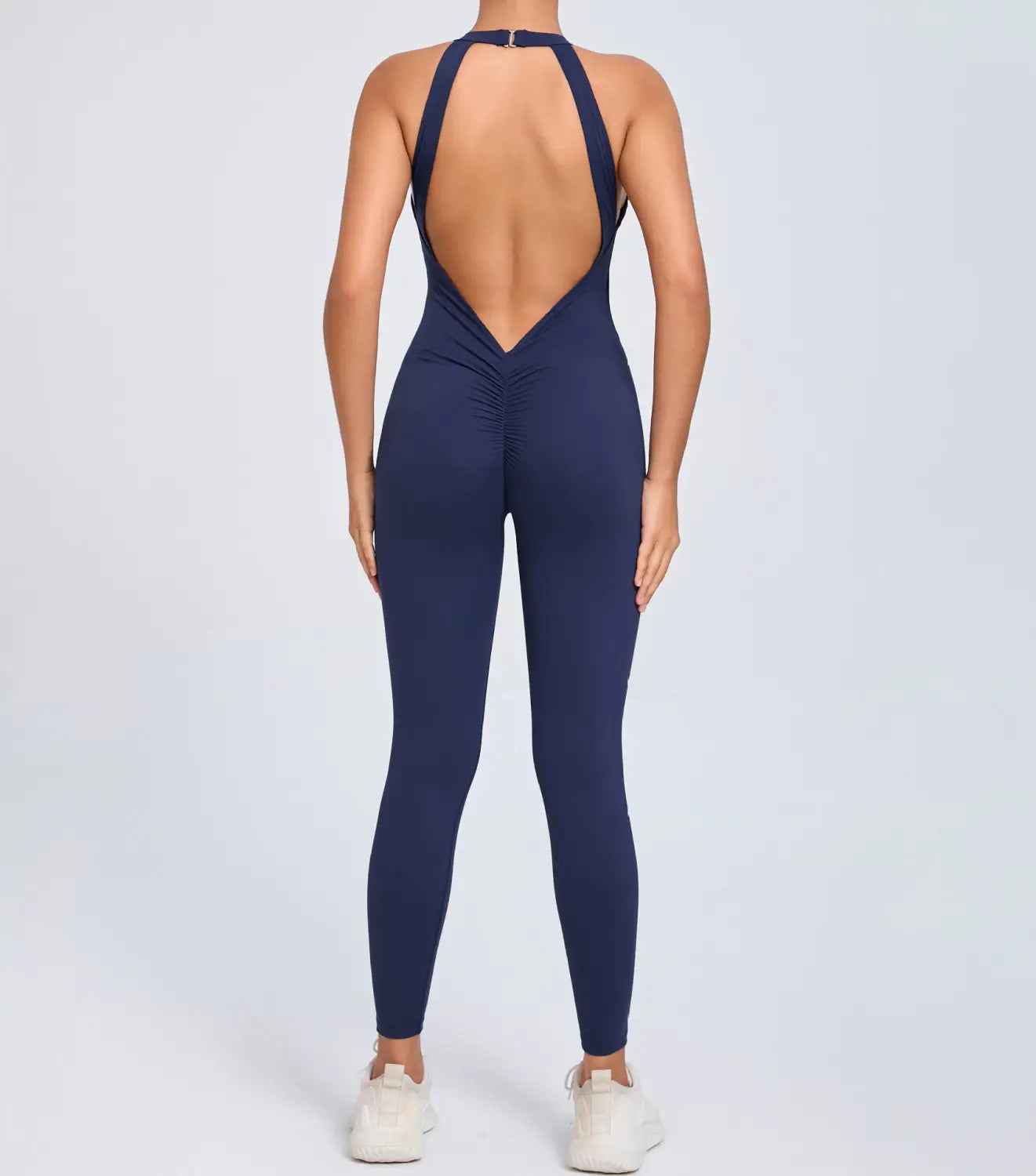 Navy blue one-piece athletic jumpsuit with halter neckline and open back design shown from the back for workout use.