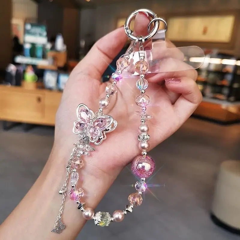 Une délicate chaîne pour téléphone à breloque papillon en cristal rose et transparent, ornée de perles étincelantes, d’accents métalliques et d’une bague à tonalité argent pour un usage avec le téléphone mobile.
